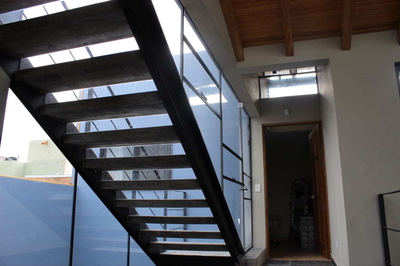 Diseño moderno de Casa Espejo con juego de luces y sombras en escaleras de concreto y cristal.