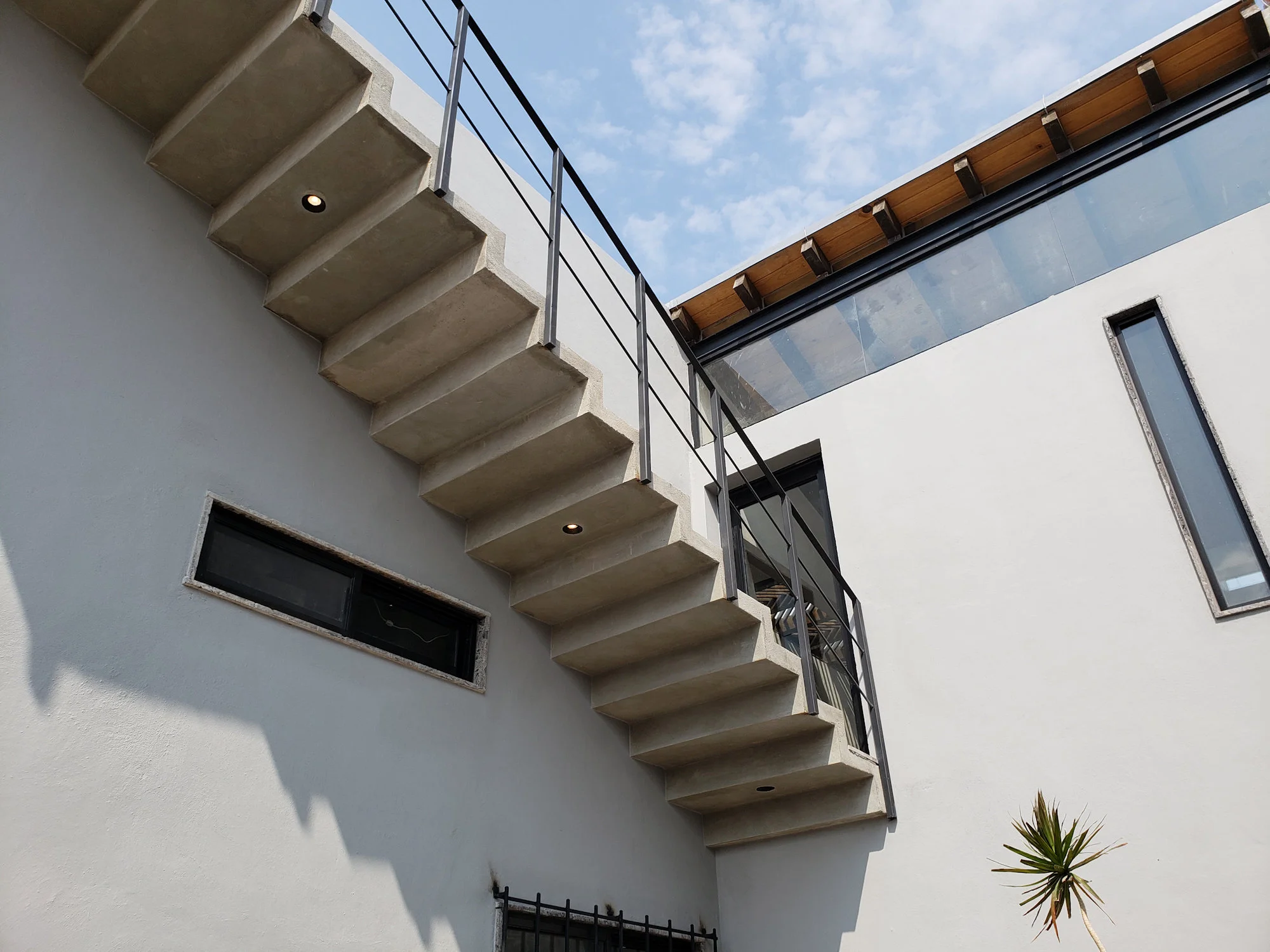 Vista exterior de Casa Dos Aguas, proyecto de arquitectura moderna con concreto expuesto y vigas de madera.